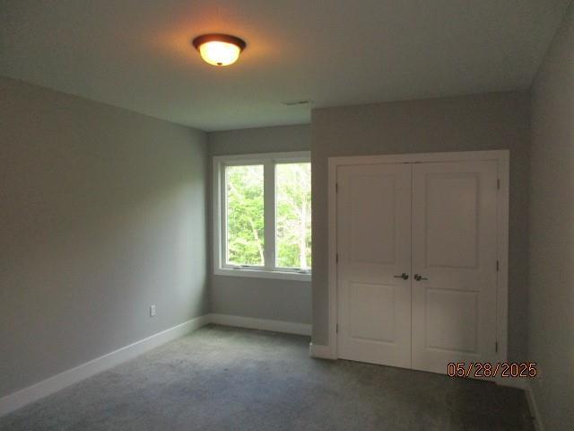 7031 N London Ave, Kansas City, MO 64151 - unfurnished bedroom featuring baseboards, carpet flooring, and a closet