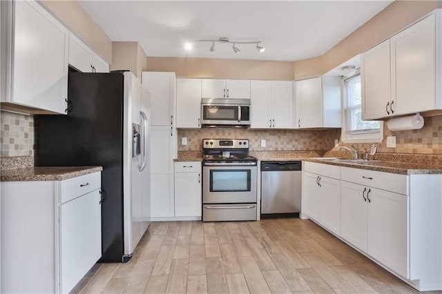 6773 N Askew Cir, Gladstone, MO 64119 - kitchen featuring stainless steel appliances, white cabinetry, light wood-type flooring, and decorative backsplash