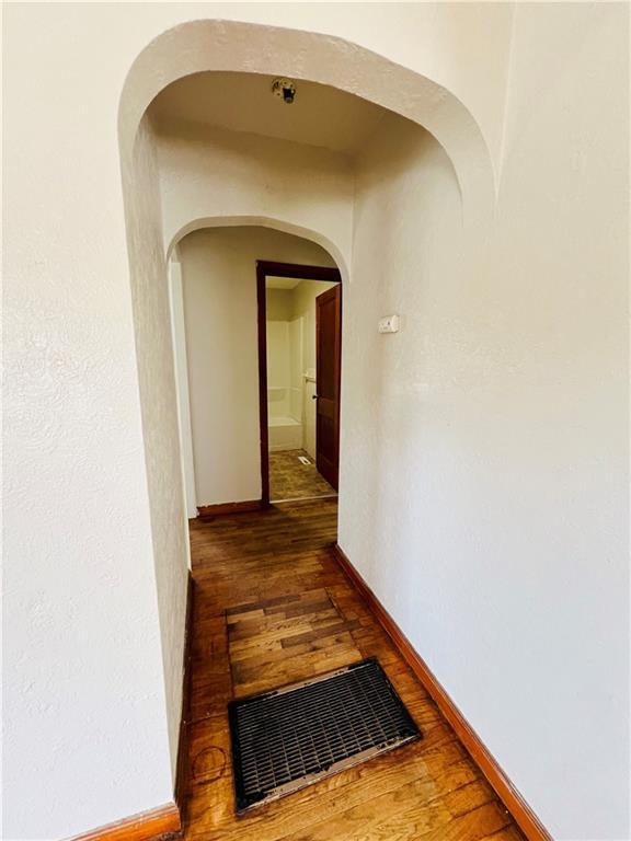 211 W 22nd St, Higginsville, MO 64037 - hall featuring arched walkways, wood finished floors, and baseboards