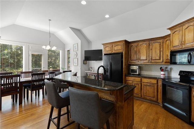 11518 W 143rd Ter, Olathe, KS 66062 - kitchen featuring black appliances, lofted ceiling, a breakfast bar area, a chandelier, and wood finished floors