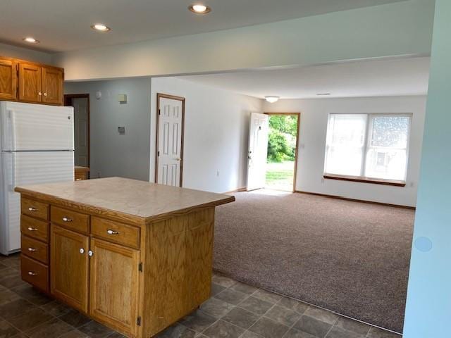 502A 3rd St, Plattsburg, MO 64477 - kitchen with freestanding refrigerator, dark colored carpet, brown cabinets, a kitchen island, and light countertops
