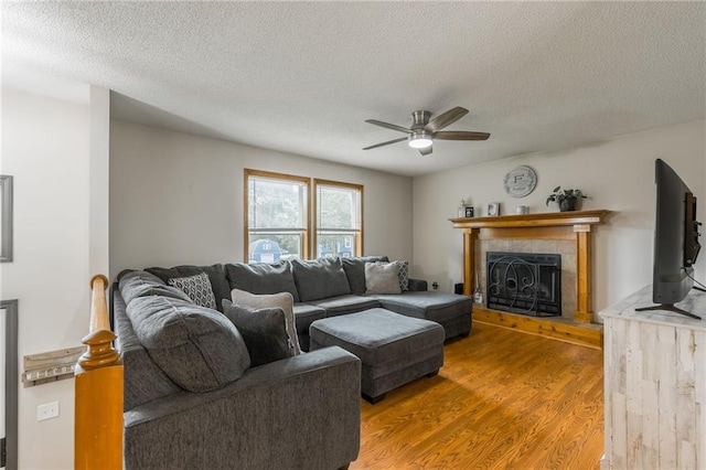 5488 SW Reed Ln, Trimble, MO 64492 - living area featuring a ceiling fan, light wood finished floors, a textured ceiling, and a tiled fireplace