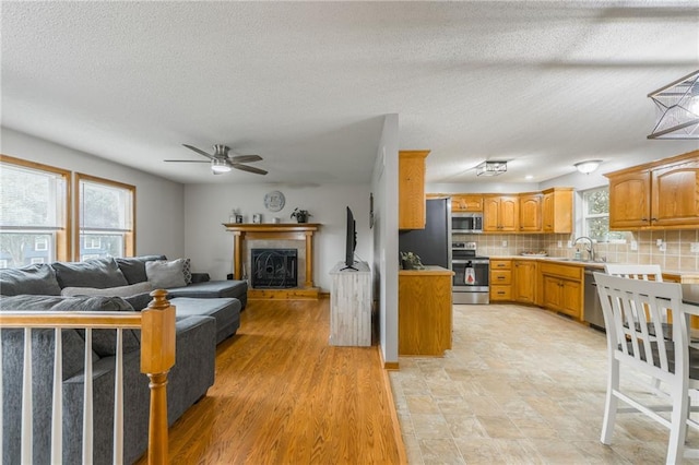 5488 SW Reed Ln, Trimble, MO 64492 - kitchen with stainless steel appliances, a ceiling fan, decorative backsplash, a textured ceiling, and open floor plan