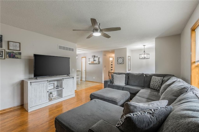 5488 SW Reed Ln, Trimble, MO 64492 - living area featuring a ceiling fan, light wood-style floors, a textured ceiling, and a chandelier
