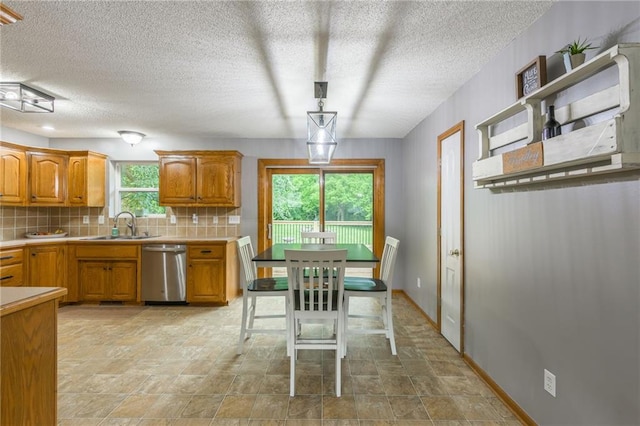 5488 SW Reed Ln, Trimble, MO 64492 - kitchen featuring stainless steel dishwasher, brown cabinets, decorative backsplash, light countertops, and stone finish floors