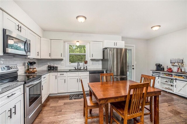 504 W 5th Ct, Peculiar, MO 64078 - kitchen with appliances with stainless steel finishes, a sink, tasteful backsplash, and wood finished floors