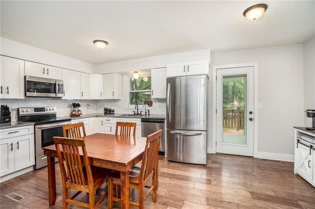 504 W 5th Ct, Peculiar, MO 64078 - kitchen with stainless steel appliances, backsplash, white cabinetry, and wood finished floors
