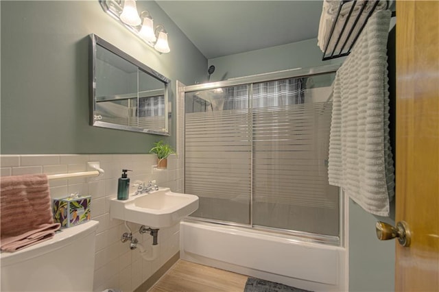 4511 NE 45th St, Kansas City, MO 64117 - full bath with bath / shower combo with glass door, tile walls, and wood finished floors