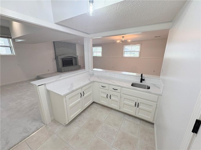 3647 NW Blue Jacket Dr, Lees Summit, MO 64064 - kitchen featuring open floor plan, a textured ceiling, a brick fireplace, white cabinets, and a peninsula