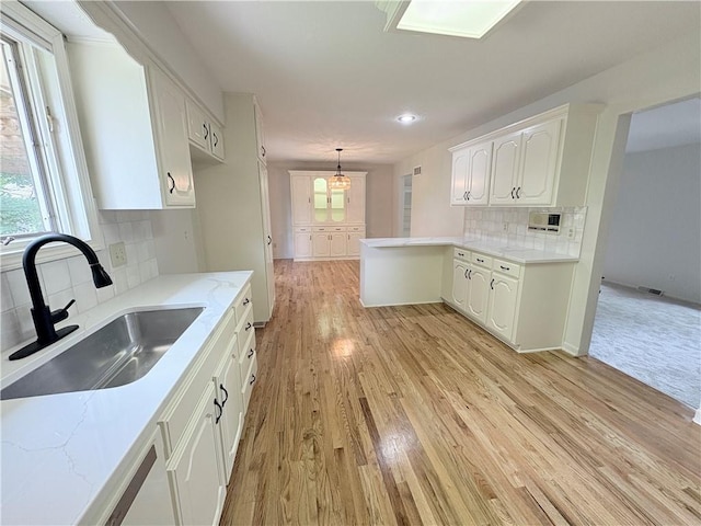 3647 NW Blue Jacket Dr, Lees Summit, MO 64064 - kitchen with white cabinets, a peninsula, backsplash, and healthy amount of natural light