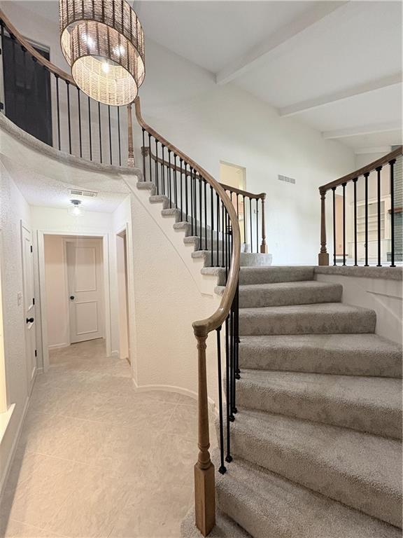 3647 NW Blue Jacket Dr, Lees Summit, MO 64064 - stairway with beamed ceiling, tile patterned flooring, and a towering ceiling
