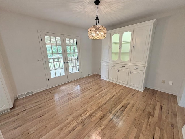 3647 NW Blue Jacket Dr, Lees Summit, MO 64064 - unfurnished dining area featuring french doors, light wood-style flooring, and a chandelier