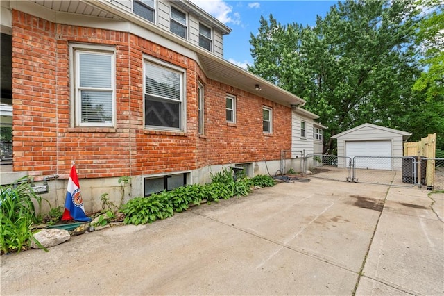 808 N River Blvd, Independence, MO 64050 - view of side of property with an outbuilding, brick siding, a detached garage, and a gate