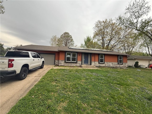 8220 Freeman Ave, Kansas City, KS 66112 - ranch-style home with a garage, stone siding, a front yard, driveway, and roof mounted solar panels