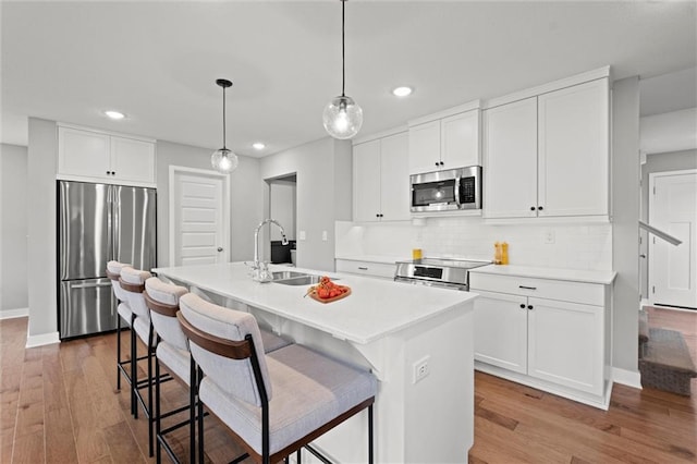8810 SW 9th Ter, Blue Springs, MO 64064 - kitchen with stainless steel appliances, recessed lighting, wood finished floors, a kitchen island with sink, and decorative backsplash