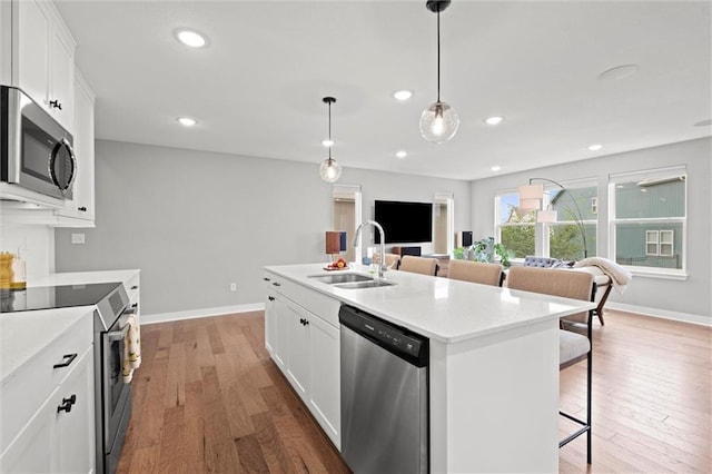 8810 SW 9th Ter, Blue Springs, MO 64064 - kitchen featuring stainless steel appliances, a kitchen breakfast bar, white cabinets, light wood finished floors, and light countertops