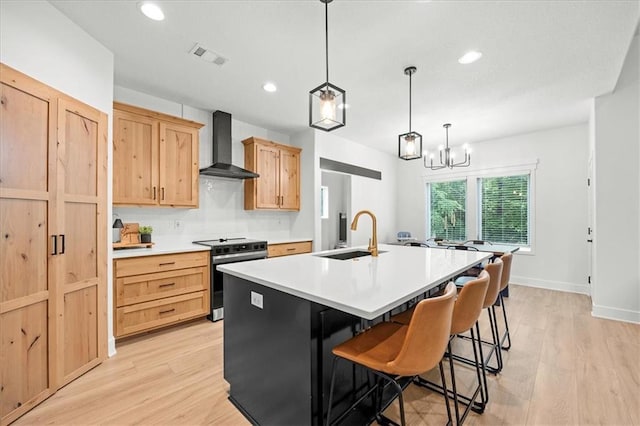 306 SW 17th St, Oak Grove, MO 64075 - kitchen with wall chimney range hood, stainless steel range oven, light wood-type flooring, light brown cabinets, and a center island with sink