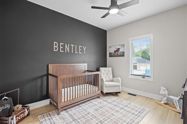 306 SW 17th St, Oak Grove, MO 64075 - bedroom with a crib, wood finished floors, and a ceiling fan