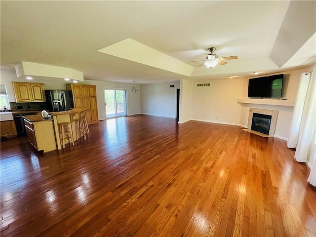 31821 159th St, Leavenworth, KS 66048 - living room with a tiled fireplace, dark wood-style floors, a ceiling fan, and a tray ceiling