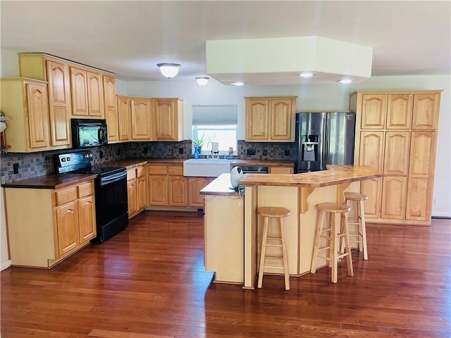31821 159th St, Leavenworth, KS 66048 - kitchen with black appliances, light brown cabinetry, a kitchen bar, and dark wood-style floors
