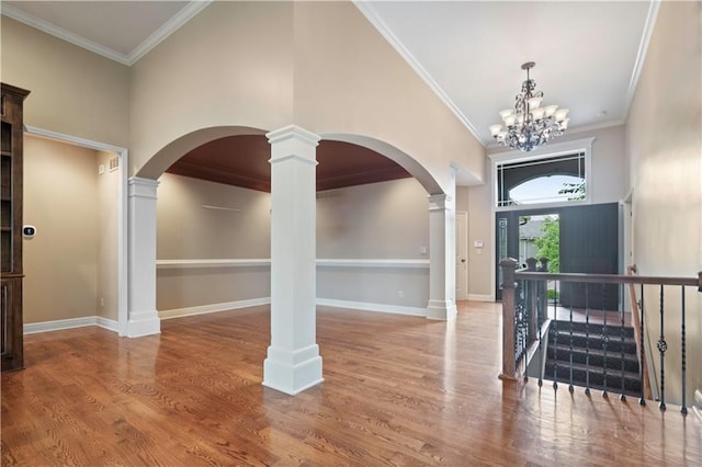 15027 Ash St, Leawood, KS 66224 - foyer featuring decorative columns, arched walkways, wood finished floors, a chandelier, and ornamental molding