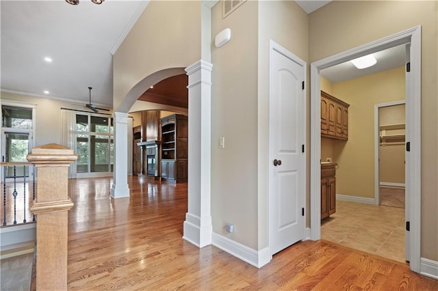 15027 Ash St, Leawood, KS 66224 - hallway with decorative columns, arched walkways, light wood-style flooring, crown molding, and recessed lighting