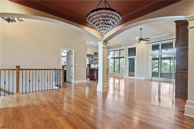 15027 Ash St, Leawood, KS 66224 - empty room with ornamental molding, a ceiling fan, decorative columns, wood finished floors, and arched walkways