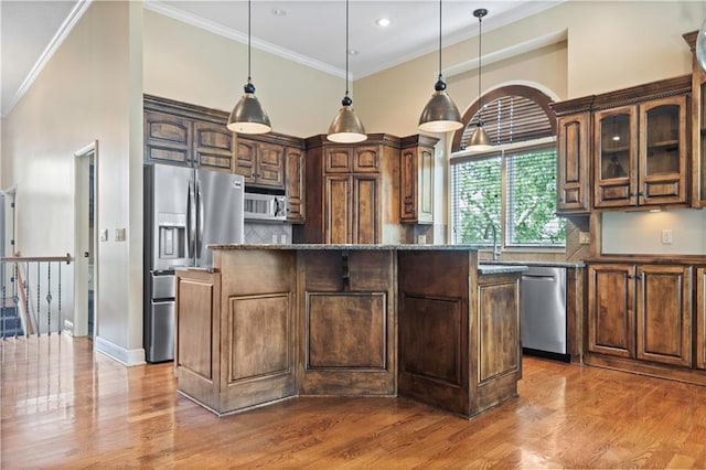 15027 Ash St, Leawood, KS 66224 - kitchen featuring appliances with stainless steel finishes, a kitchen island, wood finished floors, decorative backsplash, and ornamental molding