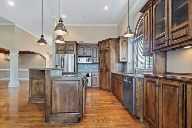 15027 Ash St, Leawood, KS 66224 - kitchen featuring ornate columns, stainless steel appliances, arched walkways, dark stone countertops, and light wood finished floors