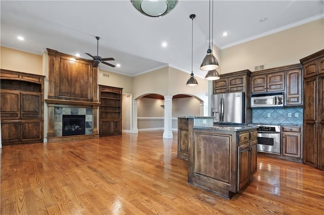 15027 Ash St, Leawood, KS 66224 - kitchen featuring decorative columns, stainless steel appliances, arched walkways, ceiling fan, and a kitchen island