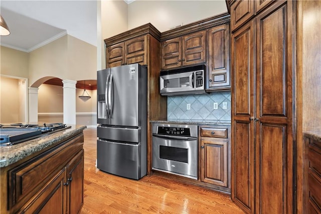 15027 Ash St, Leawood, KS 66224 - kitchen featuring stainless steel appliances, decorative columns, arched walkways, ornamental molding, and decorative backsplash