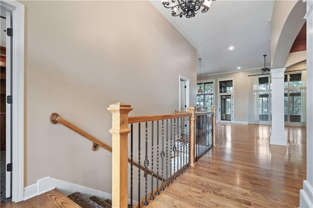 15027 Ash St, Leawood, KS 66224 - staircase with ornamental molding, wood finished floors, decorative columns, arched walkways, and a chandelier