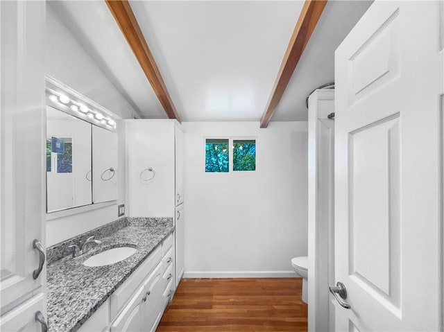 2939 Jewett St, Kansas City, MO 64117 - bathroom with toilet, beamed ceiling, vanity, wood finished floors, and baseboards
