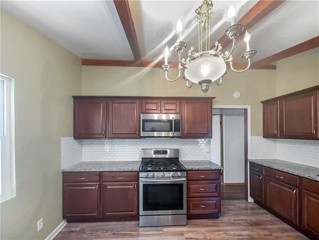 2939 Jewett St, Kansas City, MO 64117 - kitchen with appliances with stainless steel finishes, a chandelier, backsplash, dark wood-style flooring, and light stone countertops