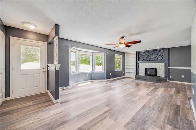 160 SW 131st Hwy, Holden, MO 64040 - unfurnished living room with a textured ceiling, ceiling fan, a fireplace, and wood finished floors