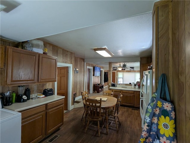 225 E 11th St, Horton, KS 66439 - kitchen with dark wood-style flooring, brown cabinets, light countertops, freestanding refrigerator, and wooden walls