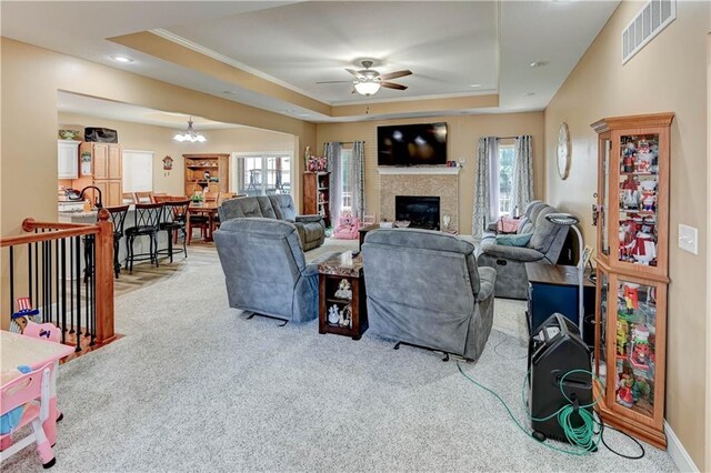 966 Moore Pl, Odessa, MO 64076 - living area with a tray ceiling, a ceiling fan, carpet flooring, a glass covered fireplace, and crown molding