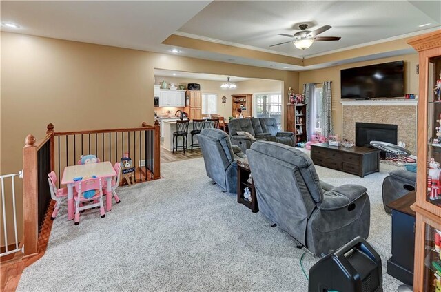 966 Moore Pl, Odessa, MO 64076 - living area with ceiling fan, ornamental molding, a raised ceiling, light carpet, and a glass covered fireplace