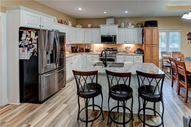 966 Moore Pl, Odessa, MO 64076 - kitchen with appliances with stainless steel finishes, white cabinetry, recessed lighting, an island with sink, and a breakfast bar area