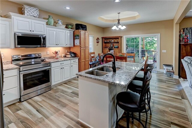 966 Moore Pl, Odessa, MO 64076 - kitchen with stainless steel appliances, a raised ceiling, light wood-style floors, a chandelier, and recessed lighting