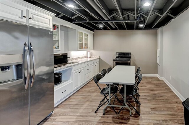 966 Moore Pl, Odessa, MO 64076 - kitchen featuring appliances with stainless steel finishes, white cabinetry, glass insert cabinets, light wood-style floors, and light stone counters