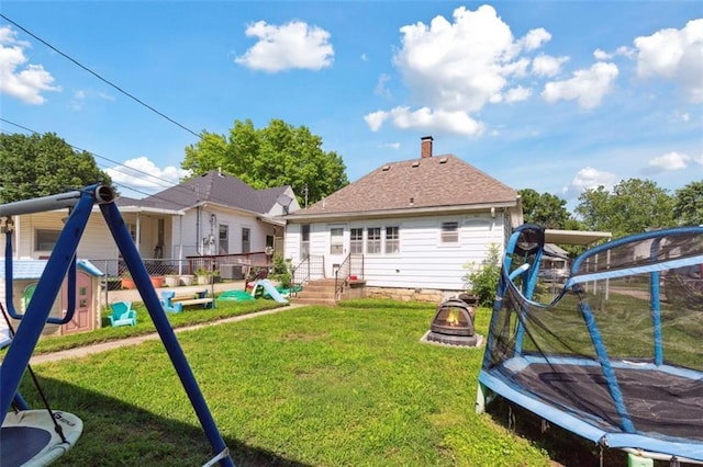 201 N Steuben Ave, Chanute, KS 66720 - rear view of property with a trampoline, an outdoor fire pit, a chimney, and entry steps