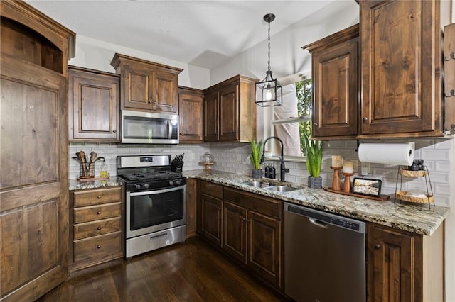 7907 W 59th Ter, Merriam, KS 66202 - kitchen with appliances with stainless steel finishes, dark wood-style flooring, light stone counters, decorative backsplash, and hanging light fixtures