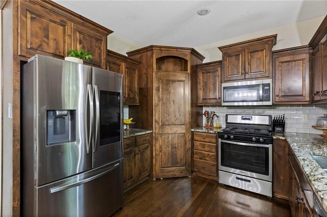 7907 W 59th Ter, Merriam, KS 66202 - kitchen featuring appliances with stainless steel finishes, stone counters, decorative backsplash, dark wood-type flooring, and dark brown cabinetry
