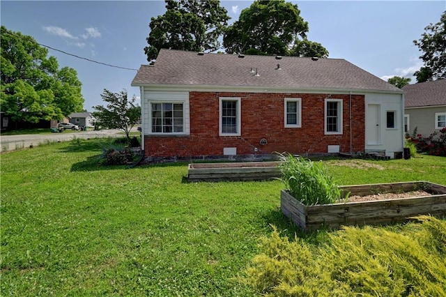 8 S Mulberry St, Louisburg, KS 66053 - rear view of house with a garden, a lawn, brick siding, and roof with shingles