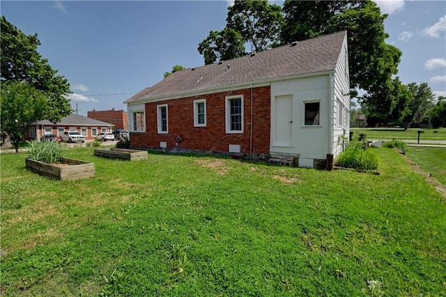 8 S Mulberry St, Louisburg, KS 66053 - rear view of house with a vegetable garden, a yard, roof with shingles, and brick siding