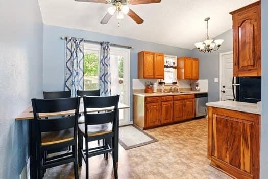 1203 S Skyline Dr, Liberty, MO 64068 - kitchen featuring dishwashing machine, a chandelier, brown cabinets, ceiling fan, and light countertops