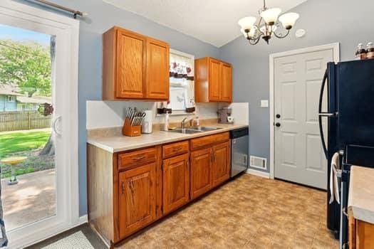 1203 S Skyline Dr, Liberty, MO 64068 - kitchen featuring lofted ceiling, dishwasher, a chandelier, light countertops, and brown cabinetry