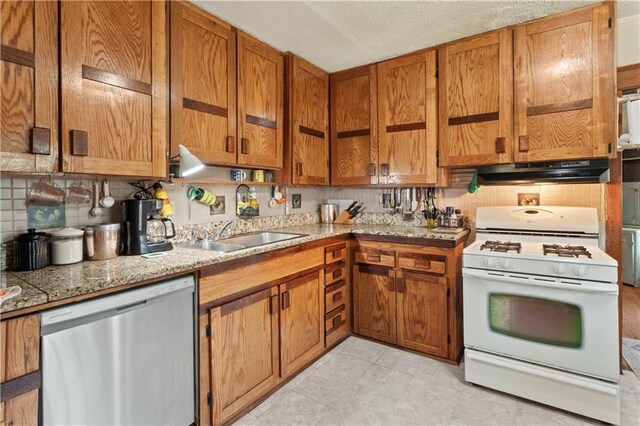 225 W Moore St, Independence, MO 64050 - kitchen with stainless steel dishwasher, white gas range, under cabinet range hood, backsplash, and brown cabinetry