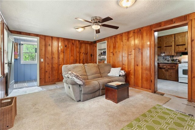 225 W Moore St, Independence, MO 64050 - living area with a ceiling fan, wood walls, a textured ceiling, and light colored carpet